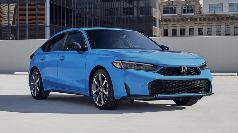 Синий хэтчбек Honda Civic Sport Touring Hybrid 2026 года, припаркованный на крыше гаража в городе