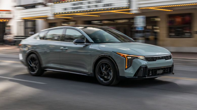бледно-бирюзовый Kia K4 2026 года проезжает мимо театра Paramount в Остине, штат Техас