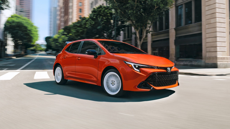 Оранжевая Toyota Corolla FX 2026 года поворачивает за угол в центре города