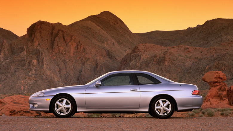 Lexus SC300 припаркован на фоне пустыни во время восхода солнца, вид слева