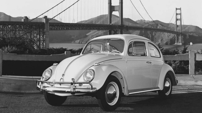 Черно-белое изображение Volkswagen Beetle, припаркованного у моста Золотые Ворота.