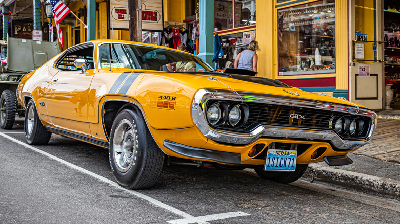 Вид спереди на 3/4 желтого Plymouth GTX 1971 года выпуска, припаркованного на улице.