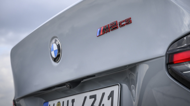 Крупным планом значок BMW M2 CS на заднем спойлере автомобиля на фоне неба