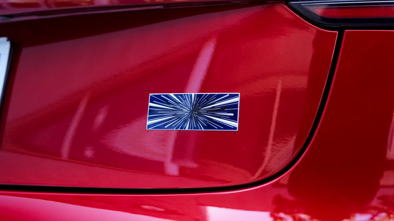 Красный Tesla Model 3 Performance 2024 года выпуска со значком на багажнике в виде звездочки.