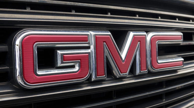 Крупный план красного логотипа GMC на серебряной решетке радиатора.