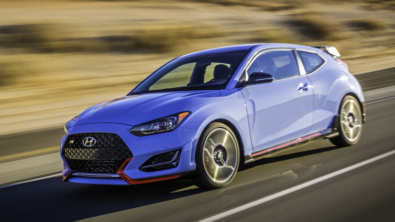 Вид спереди на 3/4 синего Hyundai Veloster N на пустынной дороге.