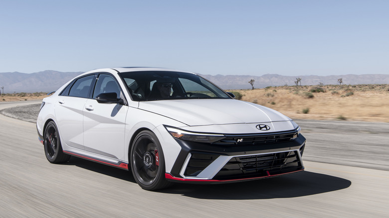 Вид спереди в 3/4 на белый Hyundai Elantra N на гоночной трассе.