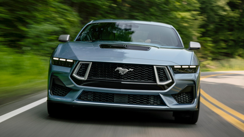 Вид спереди Ford Mustang 2025 года, едущего по проселочной дороге.