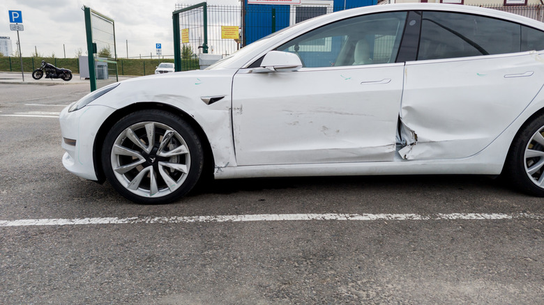 Вид сбоку на белую Tesla Model Y с повреждениями в результате аварии