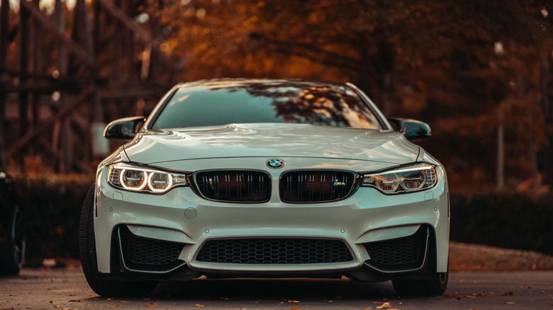 BMW M4 2020 года, припаркованный перед лесом с красными листьями, вид спереди под низким углом