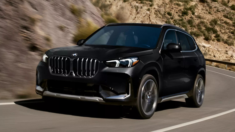 Черный BMW X1 едет по пустынной горной дороге