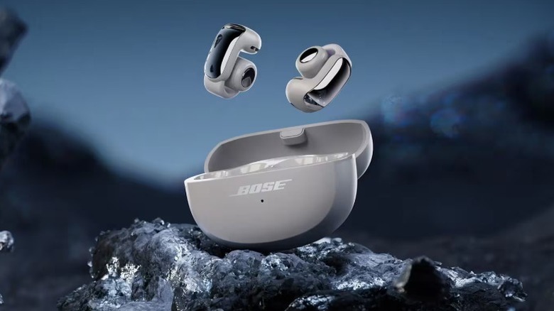 Визуализация беспроводных наушников Bose Ultra Open-Ear True Wireless и футляра в каменистой среде.