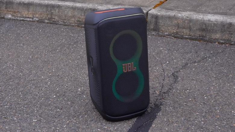 Портативная колонка для вечеринок JBL PartyBox 120 рядом с тротуаром на асфальте