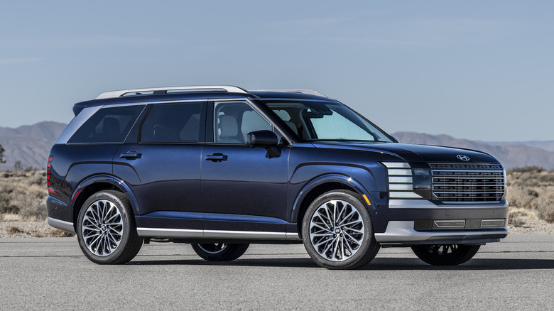 Синий Hyundai Palisade 2026 года выпуска с яркими серебряными вставками, припаркованный на дороге в пустыне.