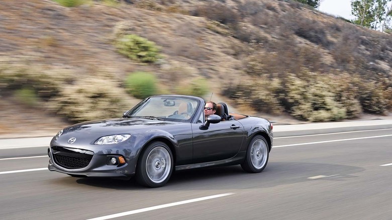 Mazda MX-5 Miata 2015 года движется по пустынной дороге, вид спереди слева в 3/4