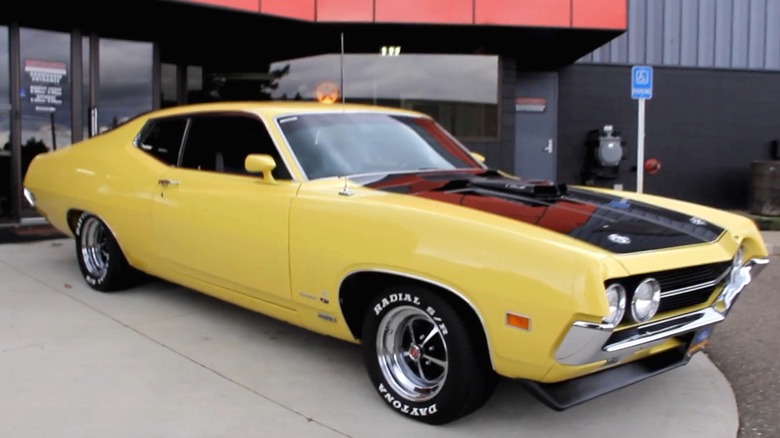 Ярко-желтый Ford Torino Cobra 1970 года выпуска с затемненным ковшом на капоте.