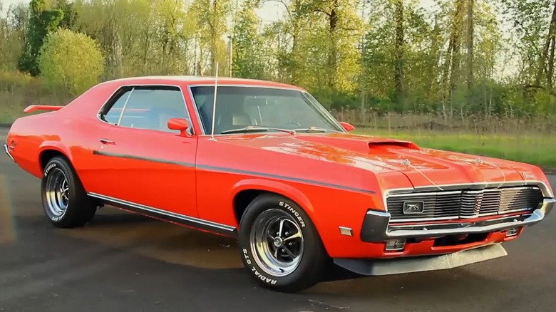 Ярко-красный Mercury Cougar Eliminator 1969 года выпуска, на заднем плане деревья.