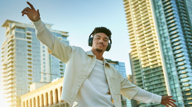 Мужчина в наушниках Bose QuietComfort на фоне городского пейзажа.