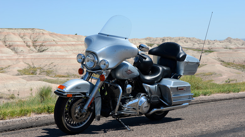 Серебристый мотоцикл Harley-Davidson Electra Glide припаркован на дороге.