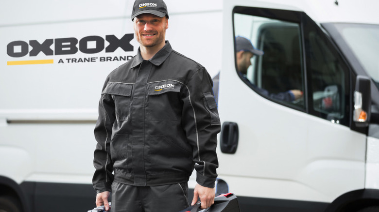 Подрядчик Oxbox стоит перед фургоном компании.