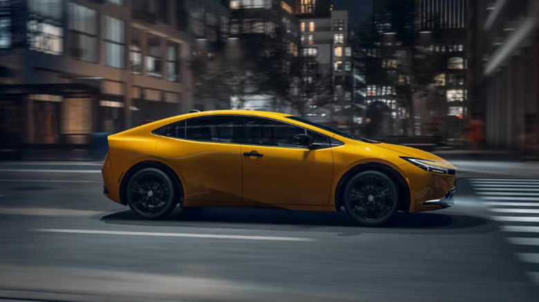 Toyota Prius 2026 года в желтом цвете быстро едет по дороге