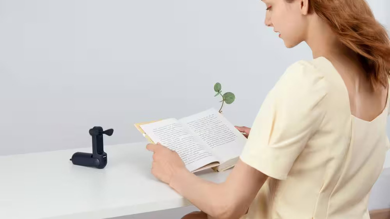 Портативный вентилятор Home Depot охлаждает женщину, читающую книгу.