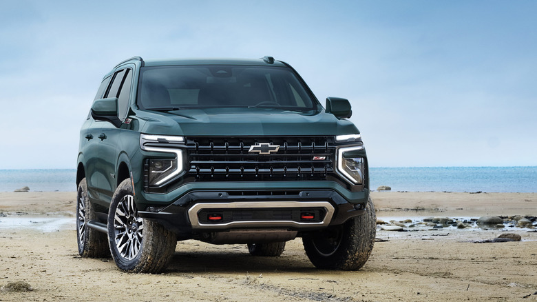 Вид спереди на зеленый Chevy Tahoe, припаркованный на пляже.