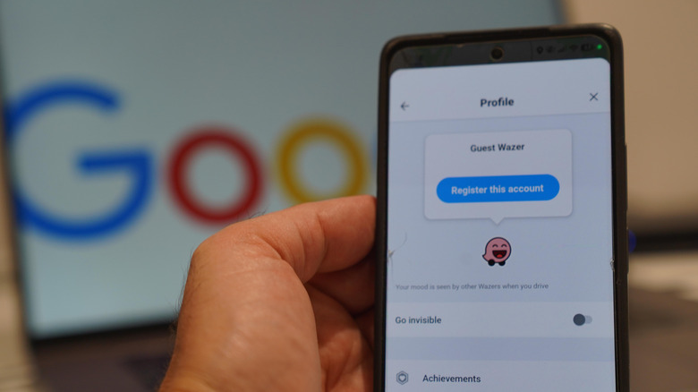 человек держит смартфон и показывает экран профиля Waze перед ноутбуком