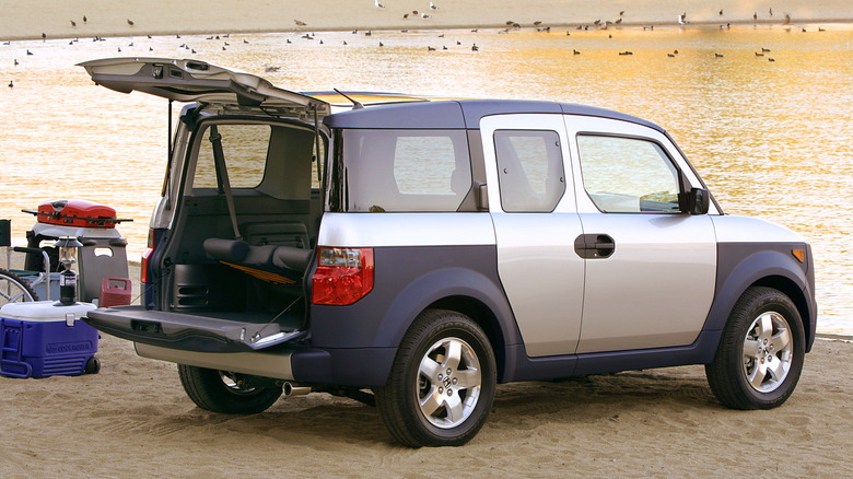 Вид сзади в 3/4 на серебристую Honda Element с открытой разделенной задней дверью.