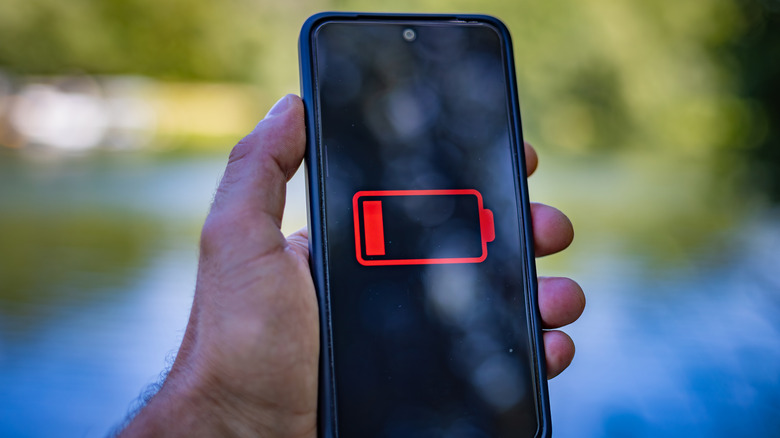 Крупный план портативного телефона Android с индикатором низкого заряда батареи на дисплее.