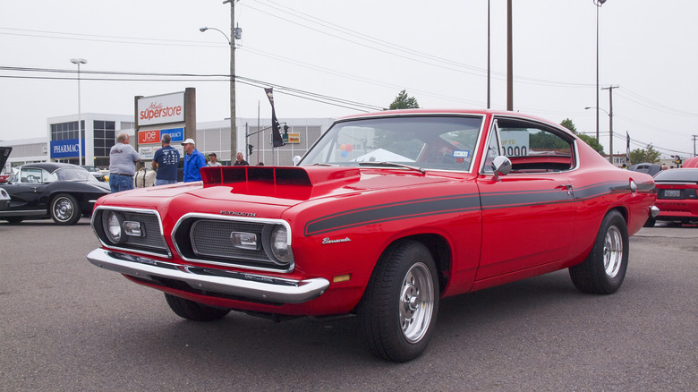 Plymouth Barracuda 1969 года с ковшом на капоте на автосалоне, вид спереди слева в 3/4, дрэг-шины, красный кузов