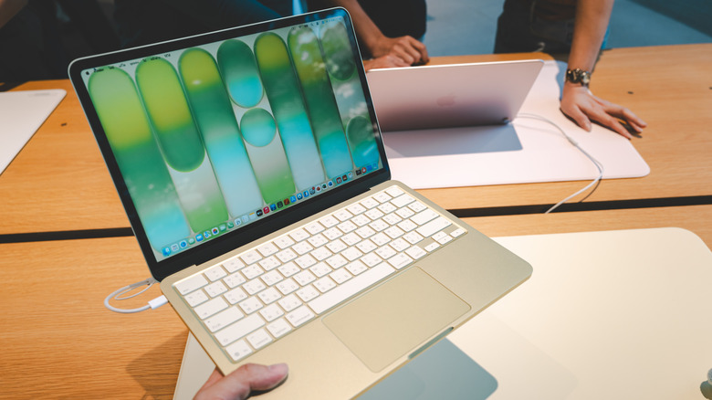 Человек, держащий ноутбук Apple MacBook Neo