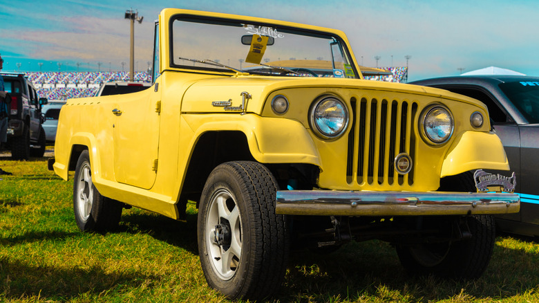 Желтый Jeepster Commando 1968 года припарковался на траве