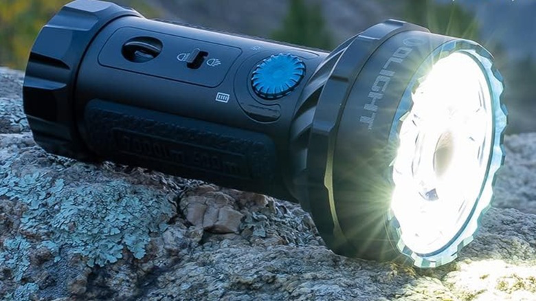 Фонарик Olight Marauder Mini на камне.