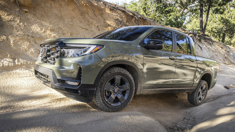 Вид спереди на 3/4 зеленого пикапа Honda Ridgeline на бездорожье.