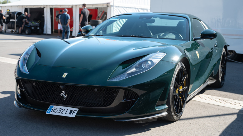 На улице припаркован темно-зеленый Ferrari 812 Superfast.