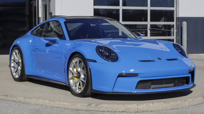 Синий Porsche 911 GT3 Touring припаркован перед автосалоном.