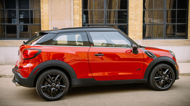 Ярко-красный MINI Paceman припаркован перед каменным зданием.