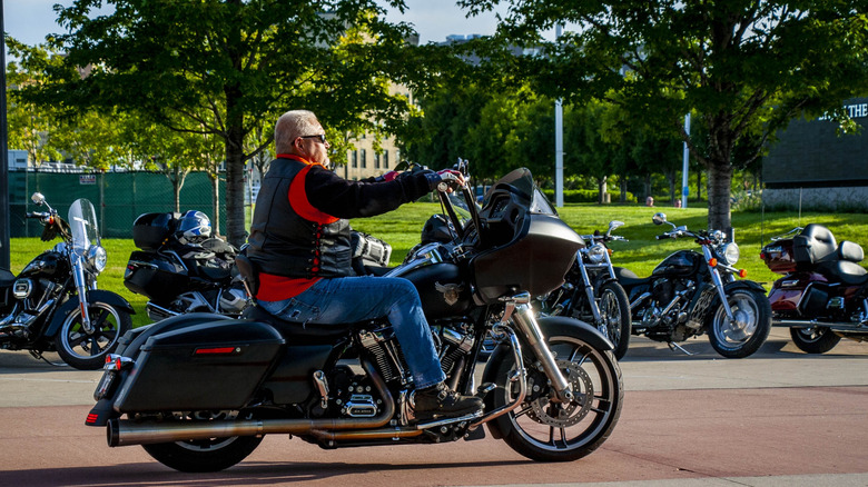 Мужчина ездит на классическом мотоцикле Harley-Davison Cruiser.