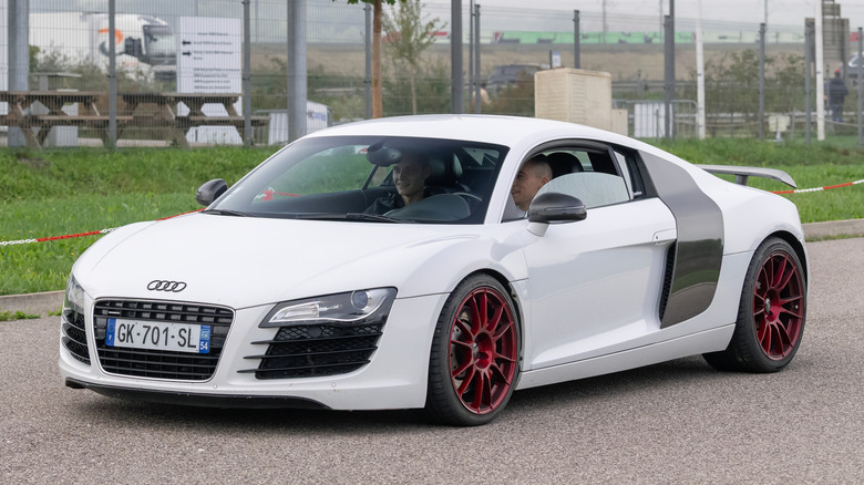 Белый Audi R8 едет по дороге.