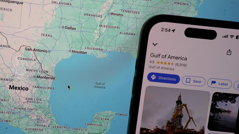 iPhone с Google Maps, показывающий Американский залив, перед экраном, на котором показана карта границы США и Мексики.