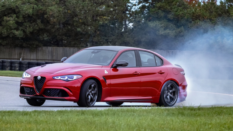 Вид спереди на 3/4 красной Alfa Romeo Giulia Quadrifoglio, дрейфующей по гоночной трассе.