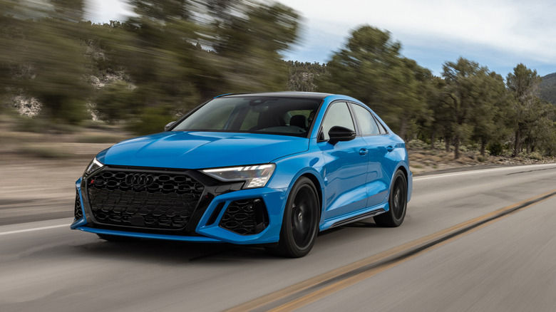 Вид спереди на 3/4 синего Audi RS 3, едущего по горной дороге.
