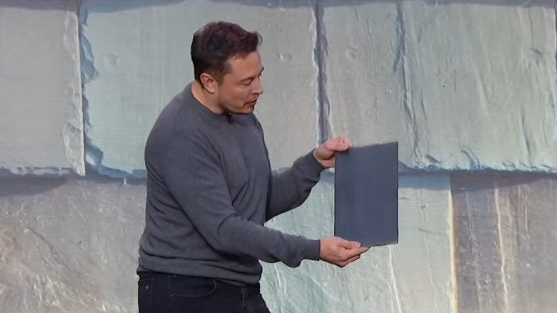 Илон Маск держит черепицу Solar Roof на презентации Solar Roof в 2016 году.