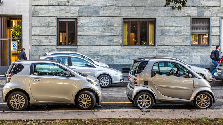 Toyota iQ припаркована позади Smart Fortwo в европейском городе, вид справа
