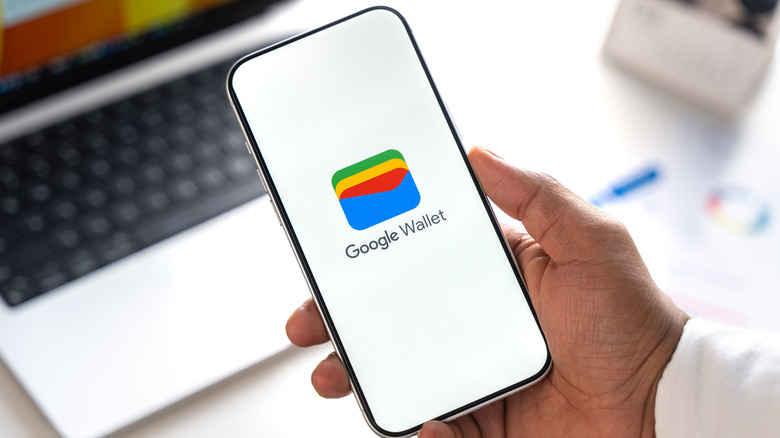 Крупный план руки, держащей телефон с экраном Google Кошелька на дисплее.