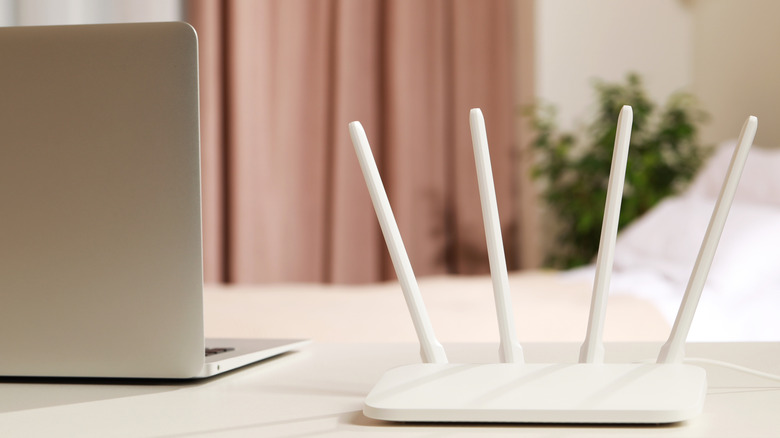 Маршрутизатор Wi-Fi на столе рядом с ноутбуком.