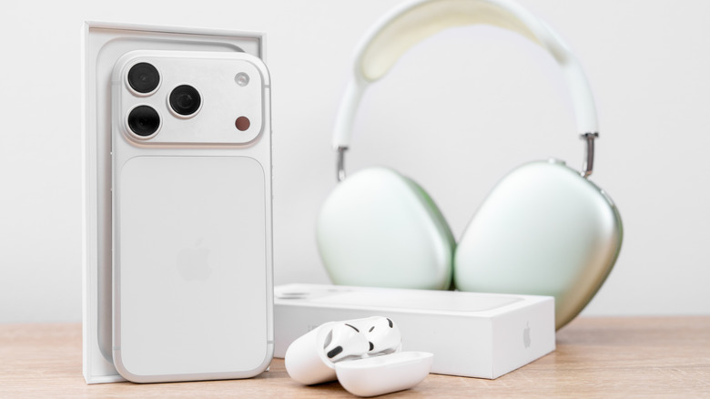 Изображение iPhone 17 Pro, AirPods Max 2 и AirPods 3 на деревянном столе.