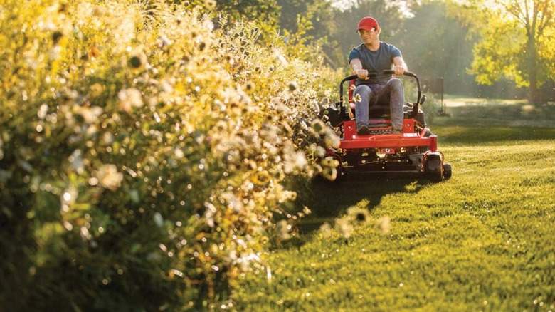 Человек косит газон косилкой с нулевым поворотом Troy-Bilt