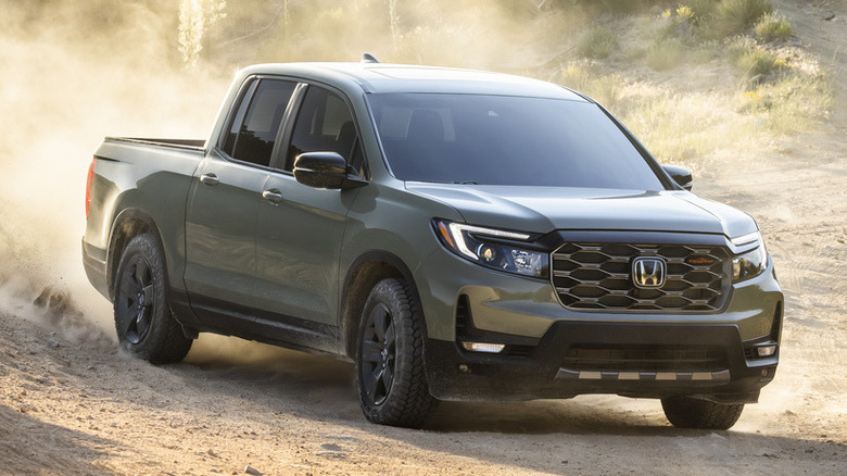 Зеленый Honda Ridgeline 2026 года выпуска едет по пыльной грунтовой дороге.